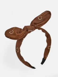 Akcesoria Do Włosów^Royalfashion Dziecięca opaska do włosów z kokardką z printem w uśmiechnięte buźki brązowy
