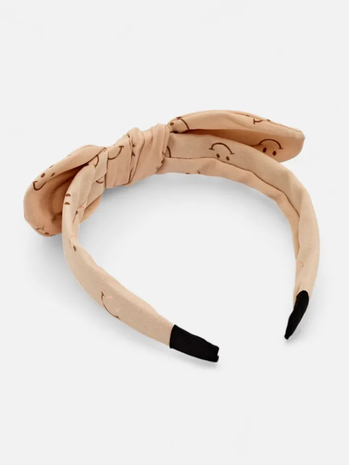 Akcesoria Do Włosów^Royalfashion Dziecięca opaska do włosów z kokardką z printem w uśmiechnięte buźki beżowy